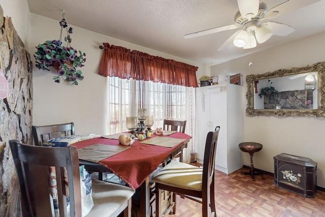 dining space featuring ceiling fan, parquet flooring, and a textured ceiling
