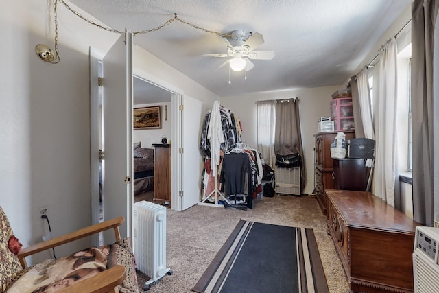 exercise room featuring ceiling fan, radiator, a textured ceiling, and carpet floors