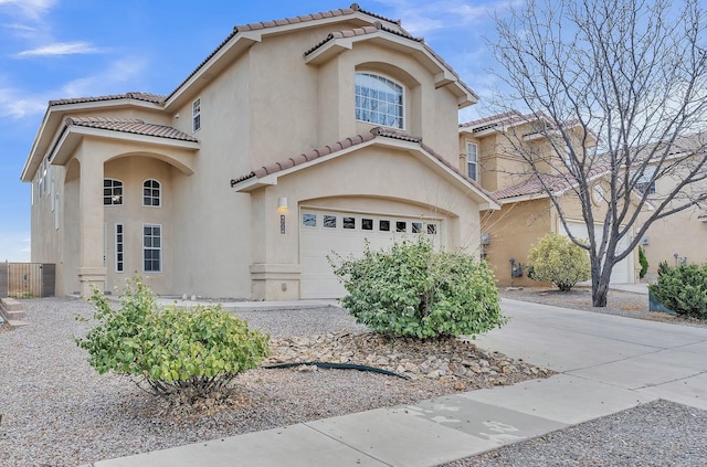 mediterranean / spanish-style house with a garage, concrete driveway, a tiled roof, and stucco siding