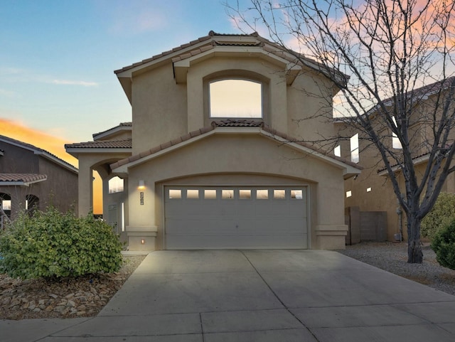 mediterranean / spanish house with concrete driveway, a tiled roof, and stucco siding