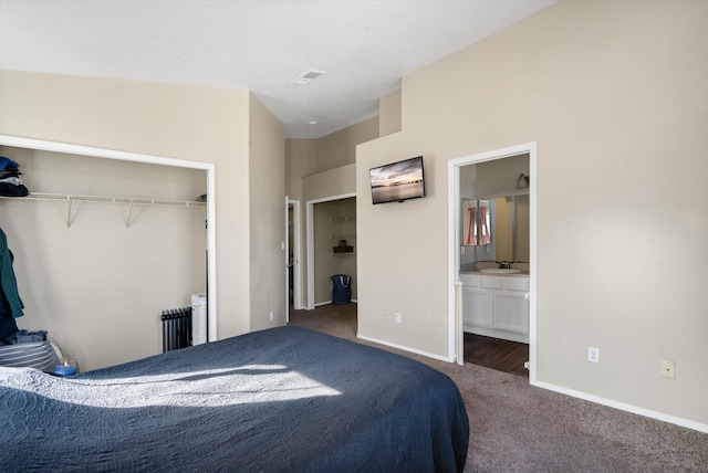 bedroom with ensuite bath, radiator heating unit, sink, a closet, and dark carpet