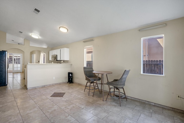 kitchen featuring a healthy amount of sunlight, appliances with stainless steel finishes, white cabinets, and lofted ceiling