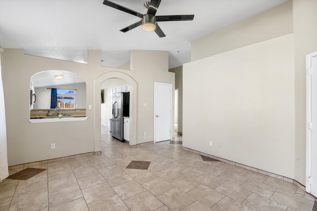 spare room featuring lofted ceiling, light tile patterned flooring, and ceiling fan