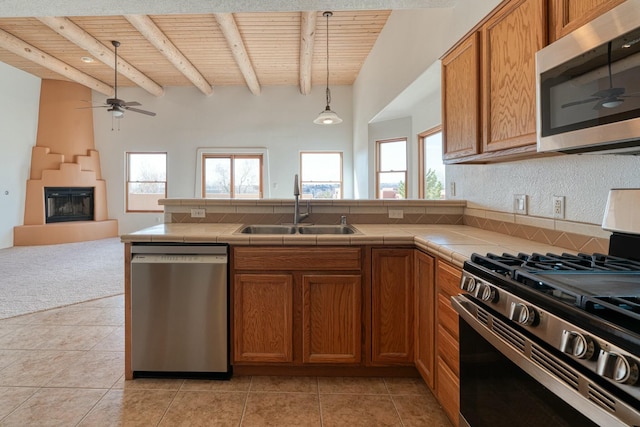 kitchen with tile countertops, wooden ceiling, stainless steel appliances, a sink, and open floor plan