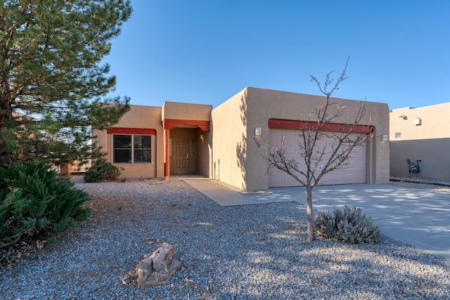 adobe home with an attached garage, concrete driveway, and stucco siding