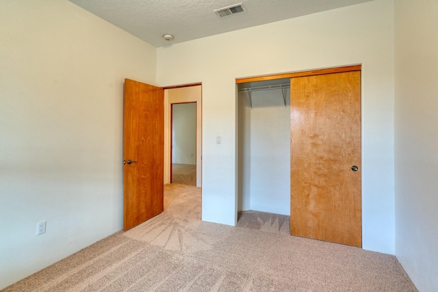 unfurnished bedroom featuring carpet floors, a closet, visible vents, and a textured ceiling