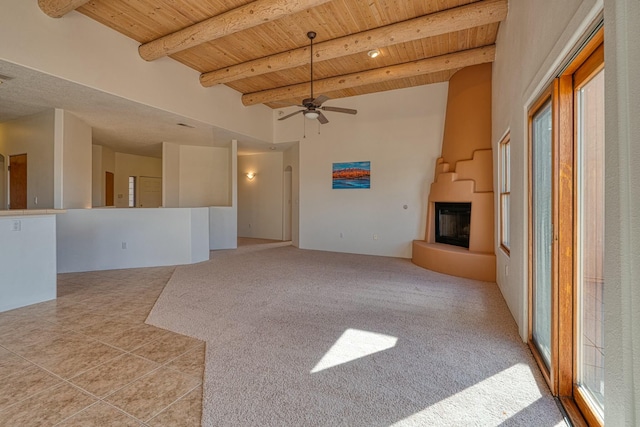 unfurnished living room with wooden ceiling, a fireplace with raised hearth, beamed ceiling, and light carpet