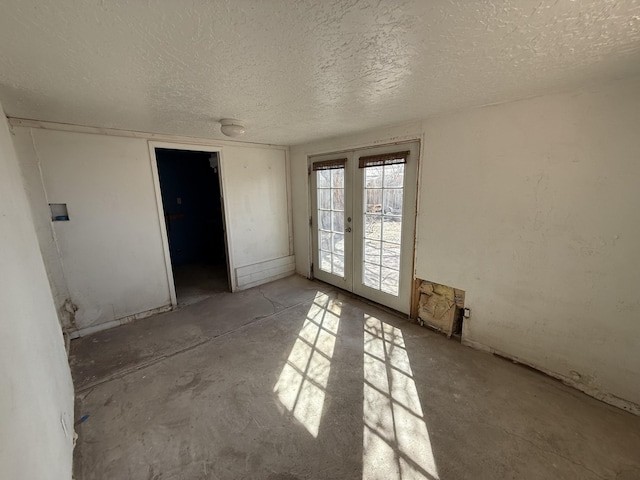 unfurnished room with french doors and a textured ceiling