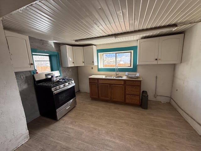 kitchen featuring white cabinets, sink, and stainless steel gas range