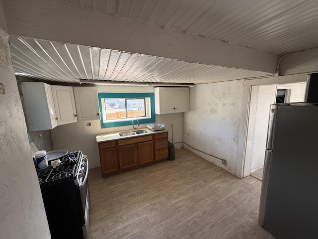 kitchen with white cabinetry, appliances with stainless steel finishes, sink, and light hardwood / wood-style floors