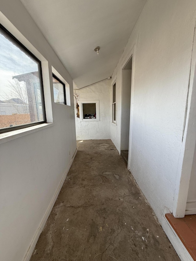 hallway featuring vaulted ceiling and concrete flooring