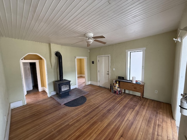 unfurnished living room with hardwood / wood-style flooring, ceiling fan, and a wood stove