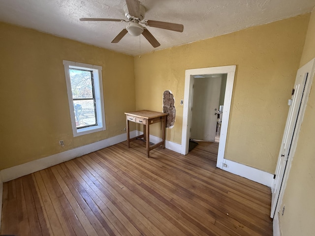 empty room featuring hardwood / wood-style flooring, ceiling fan, and a textured ceiling