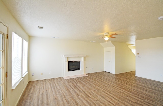 unfurnished living room with ceiling fan, light wood-type flooring, and a textured ceiling