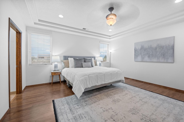 bedroom featuring hardwood / wood-style flooring, a raised ceiling, and a textured ceiling