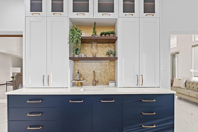 bar featuring white cabinetry, light stone countertops, sink, and blue cabinetry