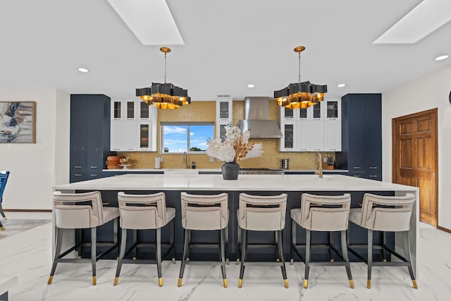 kitchen featuring a spacious island, decorative light fixtures, a breakfast bar, and wall chimney exhaust hood