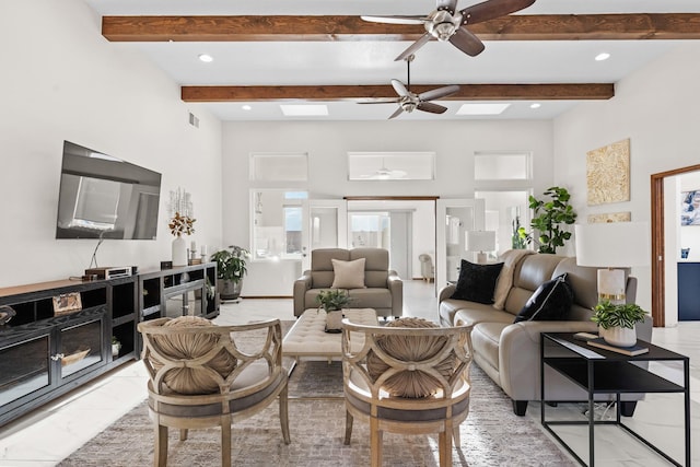 living room with ceiling fan, beam ceiling, and a skylight