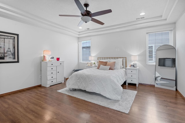 bedroom featuring hardwood / wood-style flooring, ceiling fan, and a tray ceiling