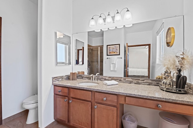 bathroom with tile patterned floors, toilet, a shower with shower door, tasteful backsplash, and vanity