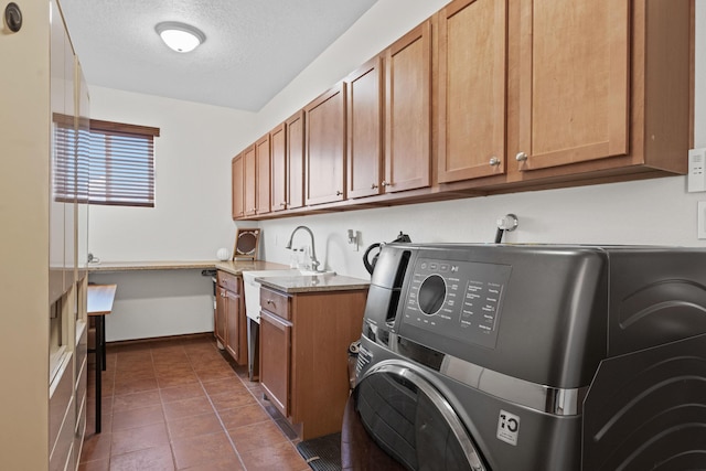 washroom featuring washer / clothes dryer, sink, dark tile patterned floors, cabinets, and a textured ceiling