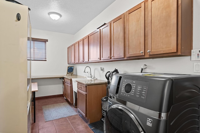 clothes washing area featuring washer / clothes dryer, sink, dark tile patterned floors, cabinets, and a textured ceiling