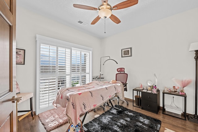 bedroom featuring ceiling fan, hardwood / wood-style floors, and a textured ceiling