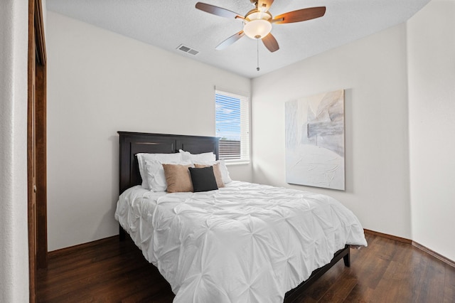 bedroom featuring dark wood-type flooring, ceiling fan, and a textured ceiling