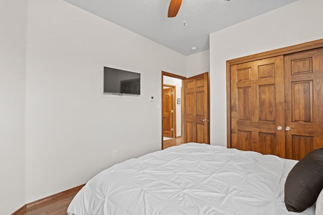 bedroom with ceiling fan, wood-type flooring, and a closet