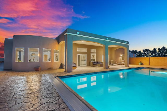 pool at dusk featuring an outdoor living space and a patio area