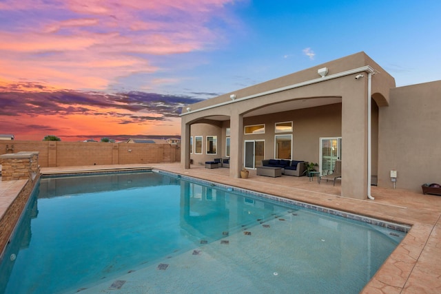 pool at dusk featuring an outdoor living space and a patio area