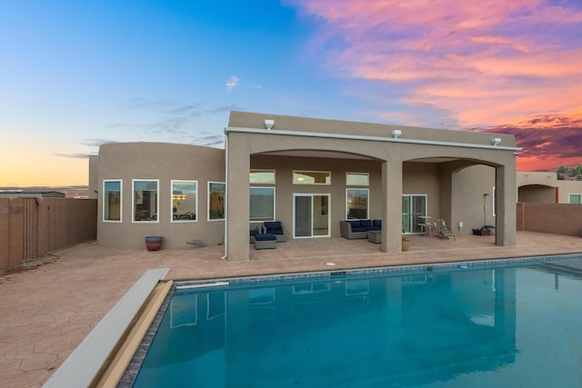 back house at dusk with a fenced in pool and a patio