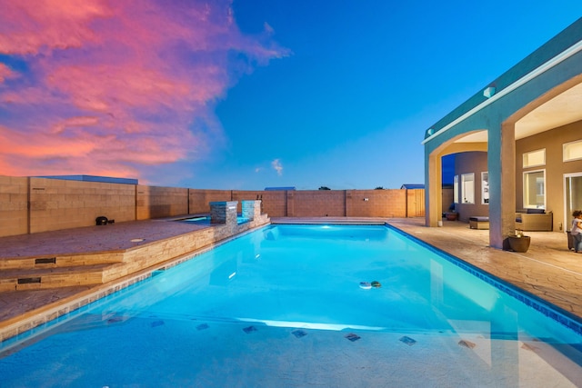 pool at dusk featuring a patio area