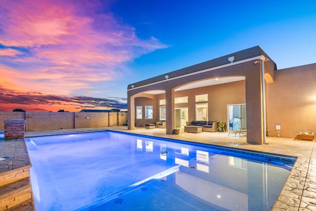 pool at dusk featuring an outdoor hangout area and a patio