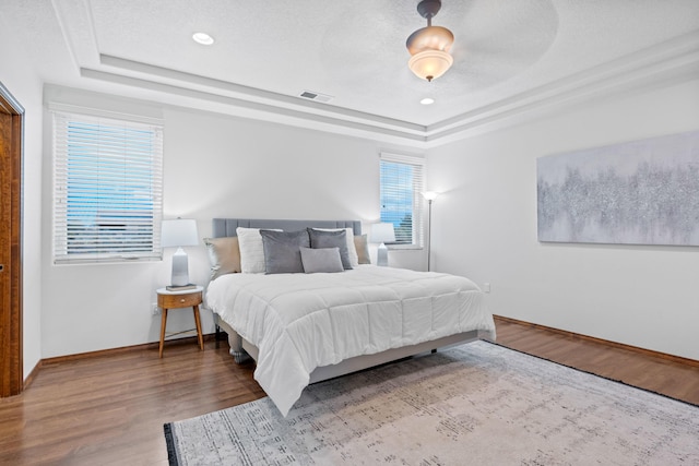 bedroom with hardwood / wood-style flooring, a raised ceiling, and a textured ceiling