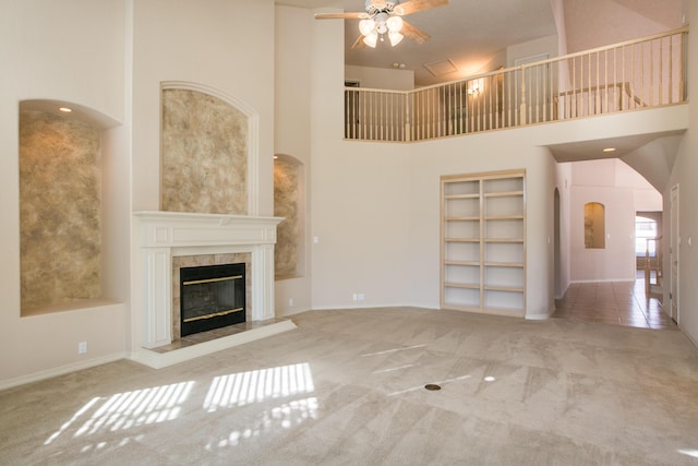 unfurnished living room with ceiling fan, a premium fireplace, carpet, and a towering ceiling