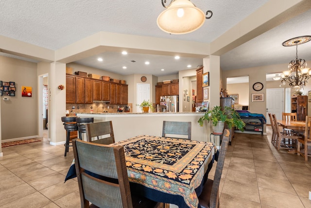 tiled dining area with a chandelier and a textured ceiling