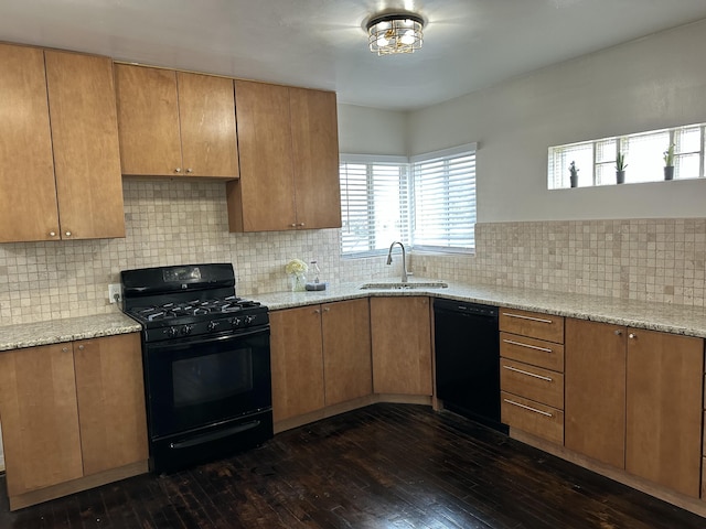 kitchen with dark wood-style flooring, a sink, black appliances, and light stone countertops