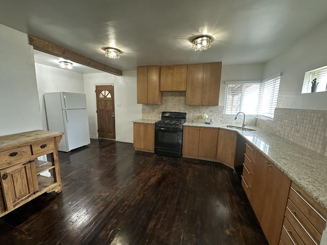 kitchen with dark wood-type flooring, a sink, backsplash, freestanding refrigerator, and black gas range oven