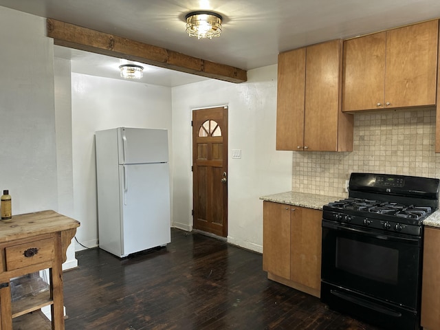 kitchen featuring black range with gas stovetop, dark wood-type flooring, backsplash, and freestanding refrigerator