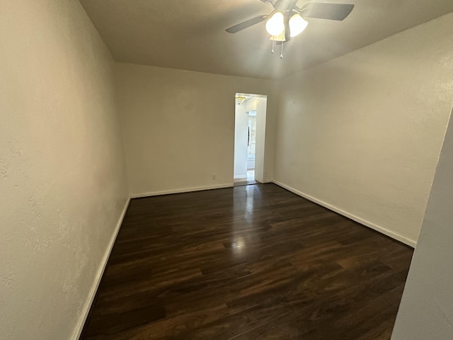 empty room featuring dark wood-style floors, ceiling fan, and baseboards