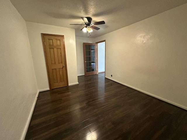 spare room featuring a ceiling fan, a textured ceiling, baseboards, and dark wood-type flooring