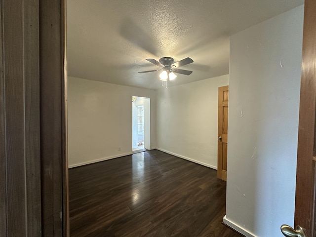 unfurnished room featuring ceiling fan, dark wood-type flooring, a textured ceiling, and baseboards