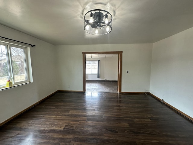 empty room featuring dark wood-style flooring, plenty of natural light, and baseboards