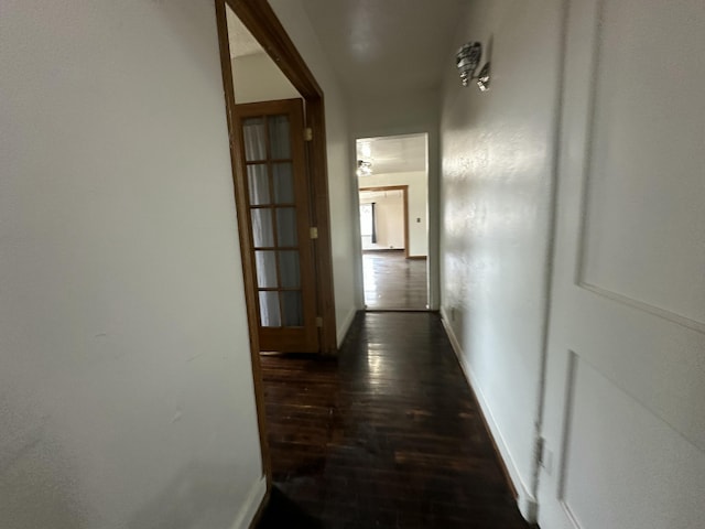 hallway with dark wood-type flooring and baseboards