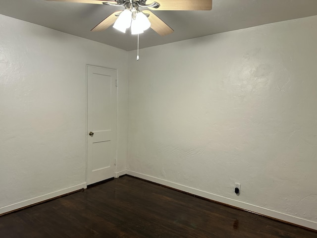 unfurnished room with dark wood-type flooring, a ceiling fan, and baseboards