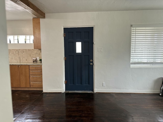 entryway with beam ceiling, baseboards, dark wood-style flooring, and a textured wall