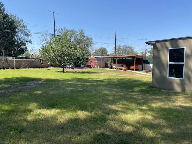 view of yard with an outbuilding, fence, and a storage unit