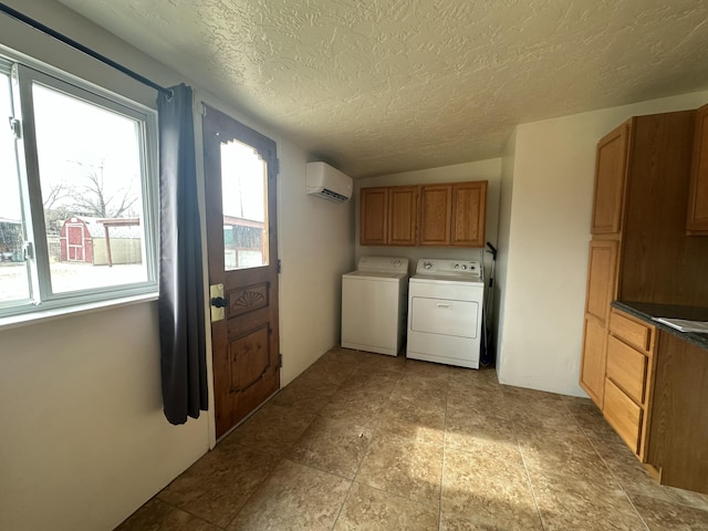 laundry area with a wall unit AC, cabinet space, separate washer and dryer, and a textured ceiling