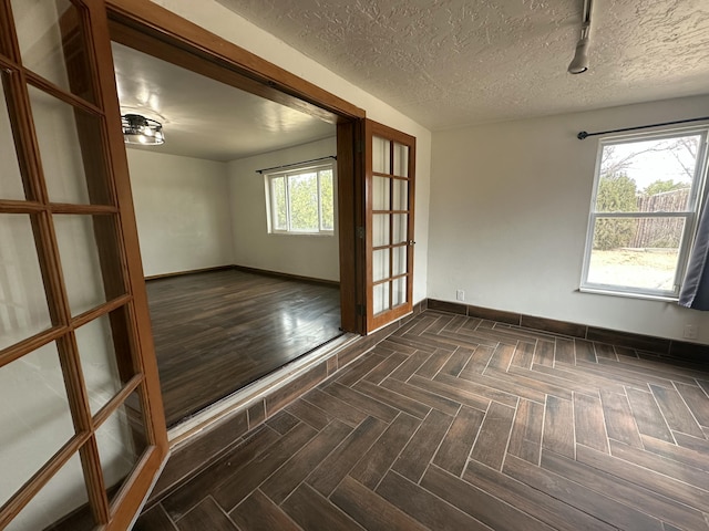 empty room featuring parquet flooring, baseboards, and a textured ceiling